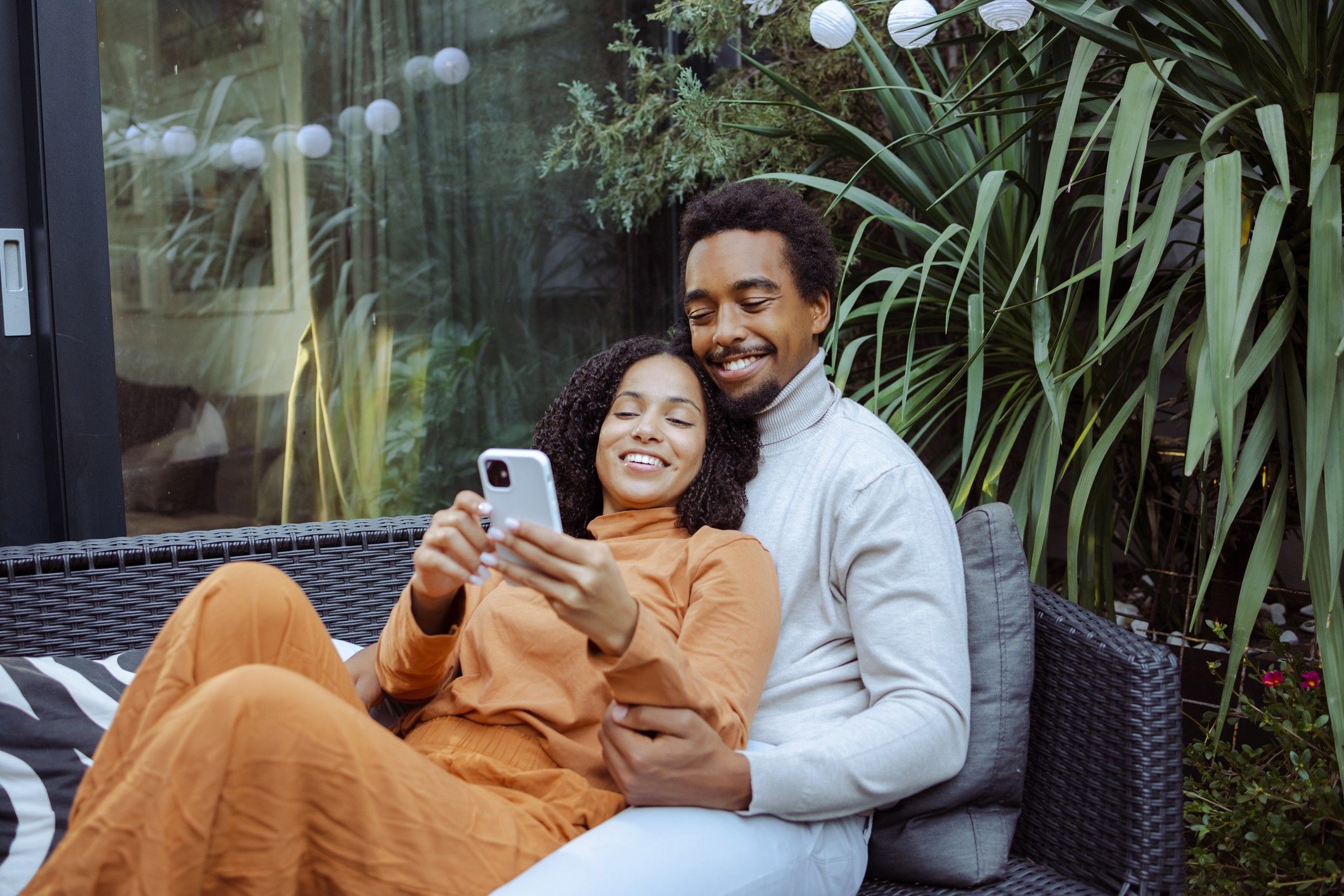 Happy-young-African-American-couple-enjoying-leisure-time-together-while-scrolling-phone-dating-apps